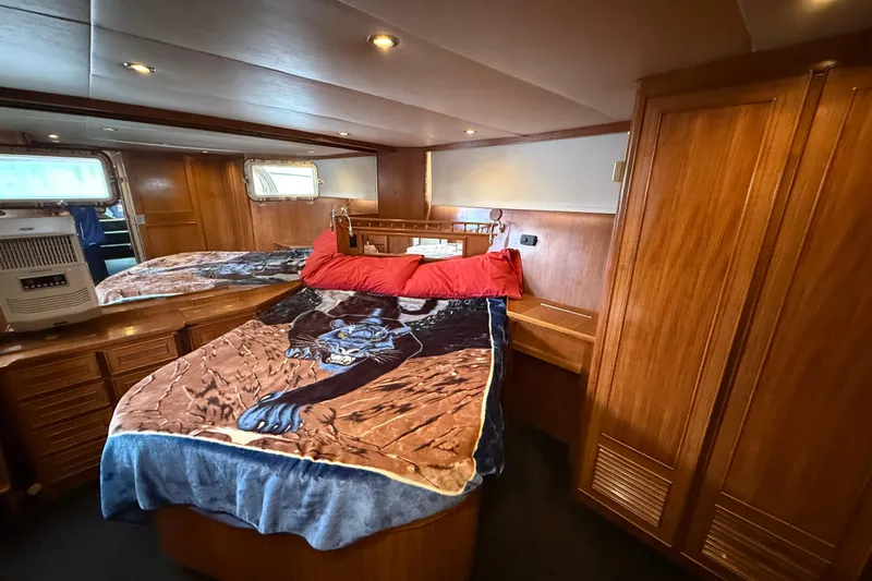 Qui-si-sana Yacht Photos Pics Cozy cabin interior of 1989 Jefferson 52 Victory yacht with wooden furnishings and decorative bedding.