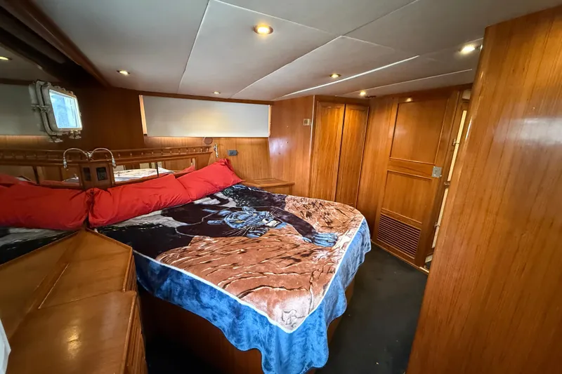Qui-si-sana Yacht Photos Pics Cozy bedroom in 1989 Jefferson 52 Victory yacht with wood paneling and nautical decor.