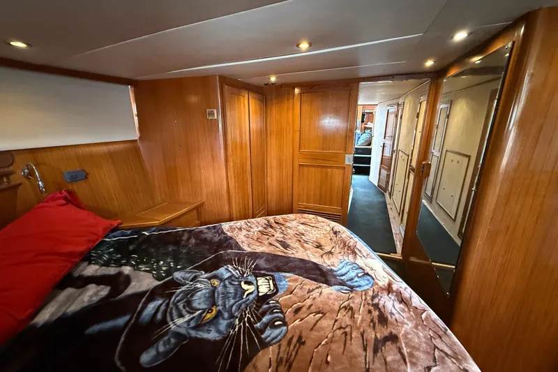 Qui-si-sana Yacht Photos Pics Cozy bedroom in 1989 Jefferson 52 Victory yacht with panther-themed blanket and wooden interior.