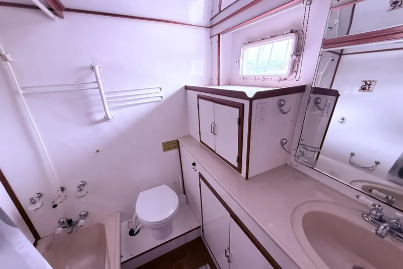 Qui-si-sana Yacht Photos Pics Bathroom interior of 1989 Jefferson 52 Victory yacht, featuring sink, toilet, and storage cabinets.