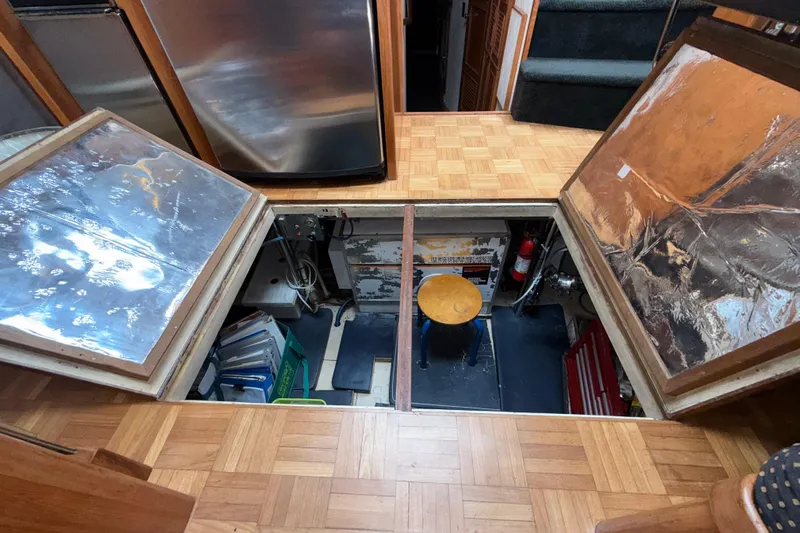 Qui-si-sana Yacht Photos Pics Engine room access in 1989 Jefferson 52 Victory yacht, featuring parquet flooring and storage compartments.