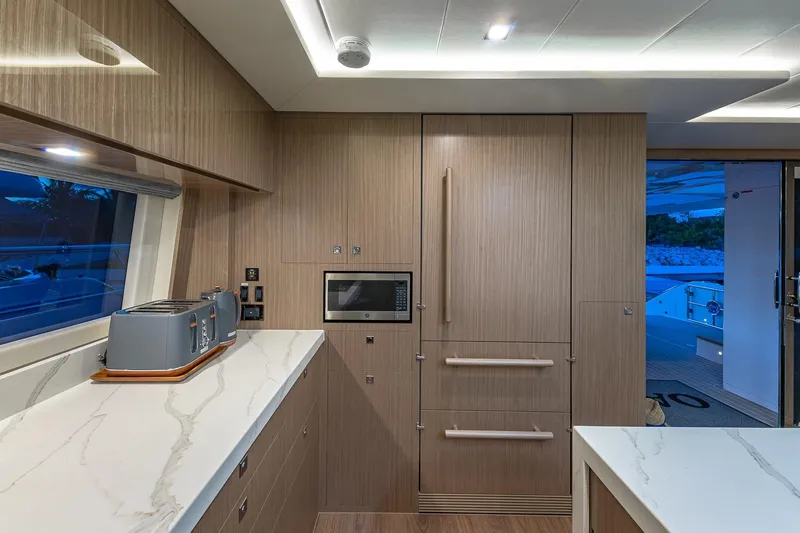 Oasis Yacht Photos Pics Modern yacht kitchen interior with wood paneling, marble countertops, and built-in appliances on Horizon PC60.
