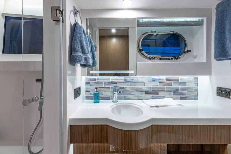Oasis Yacht Photos Pics Modern yacht bathroom with sleek design, featuring a porthole window and elegant blue accents.