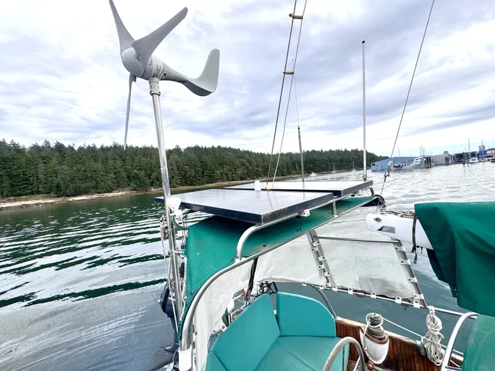  Yacht Photos Pics 1980 Hans Christian 38 MKII sailboat with solar panel and wind turbine, docked near forested shoreline.