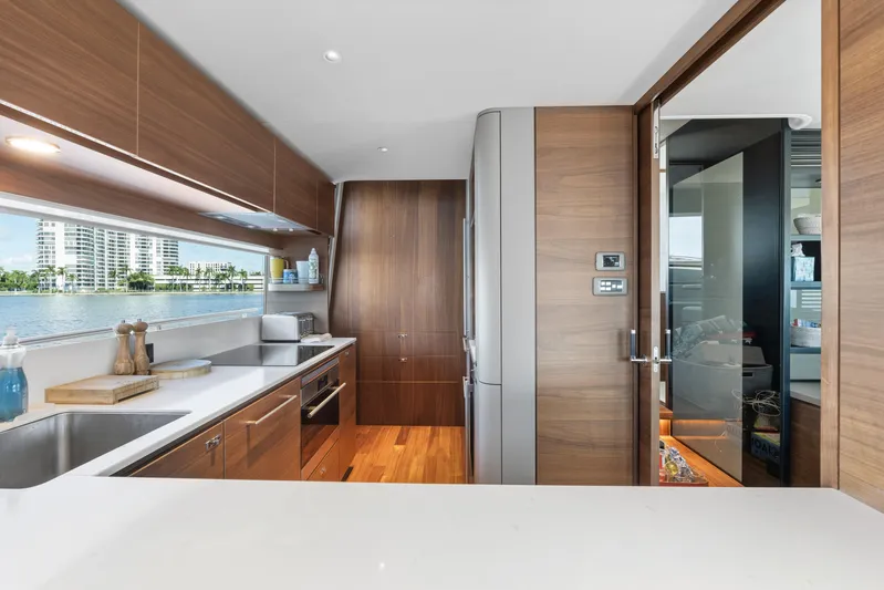  Yacht Photos Pics Luxurious kitchen interior on 2022 Princess Y85 yacht with modern wood cabinetry and scenic window view.