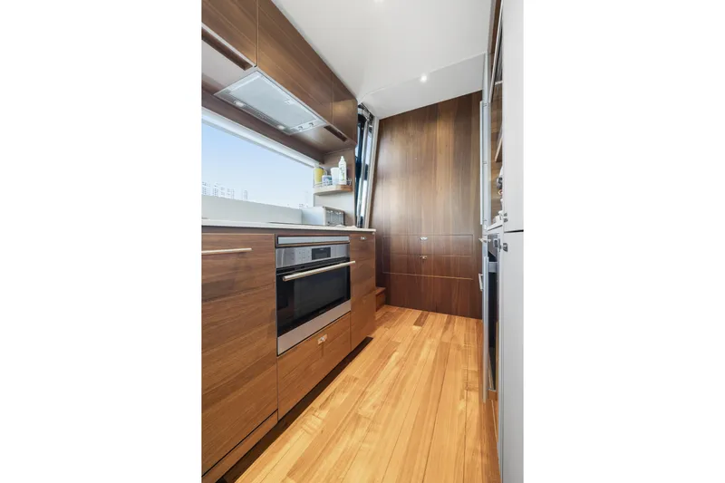  Yacht Photos Pics Modern kitchen interior on 2022 Princess Y85 yacht, featuring sleek wood cabinetry and appliances.