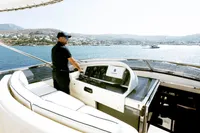 Man steering 2004 Leopard 26 Flybridge yacht on open water.