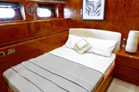 Luxurious bedroom in a 2004 Leopard 26 Flybridge yacht with elegant wood paneling.