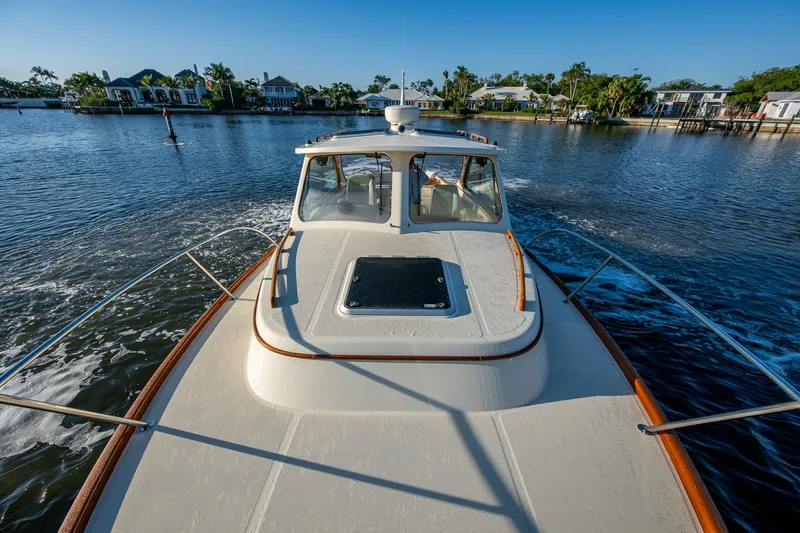 Niniane Yacht Photos Pics 2016 Hinckley Talaria 34 cruising on a serene waterway with waterfront homes in the background.