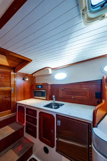 Niniane Yacht Photos Pics 2016 Hinckley Talaria 34 yacht interior with wooden cabinetry and compact kitchen area.