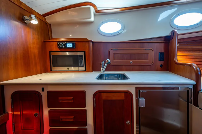 Niniane Yacht Photos Pics Interior of 2016 Hinckley Talaria 34 yacht kitchen with sink, microwave, and wooden cabinetry.
