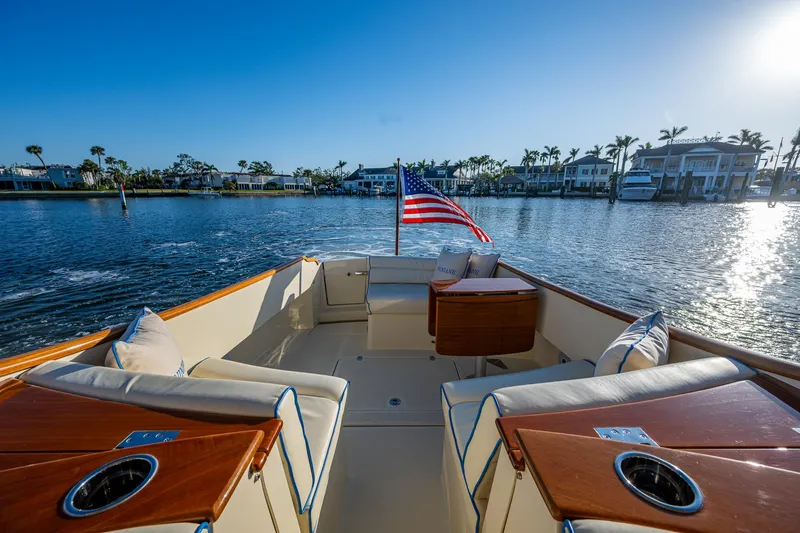 Niniane Yacht Photos Pics 2016 Hinckley Talaria 34 boat with elegant seating, American flag, and scenic waterfront view.