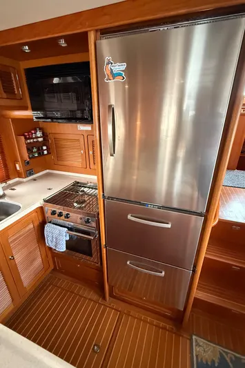 Marco Polo Yacht Photos Pics 2004 Selene Pilothouse kitchen with stainless steel fridge, stove, and wooden cabinetry.