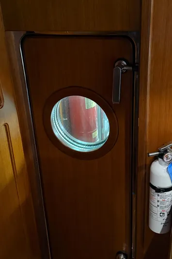 Marco Polo Yacht Photos Pics Wooden door with porthole on 2004 Selene Pilothouse, featuring a fire extinguisher nearby.