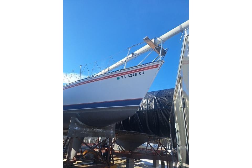 1983 Express 30 sailboat on stands under clear blue sky.