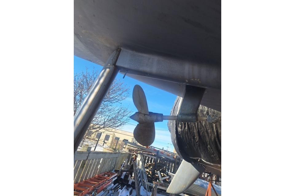 1983 Express 30 boat propeller and rudder under clear blue sky.