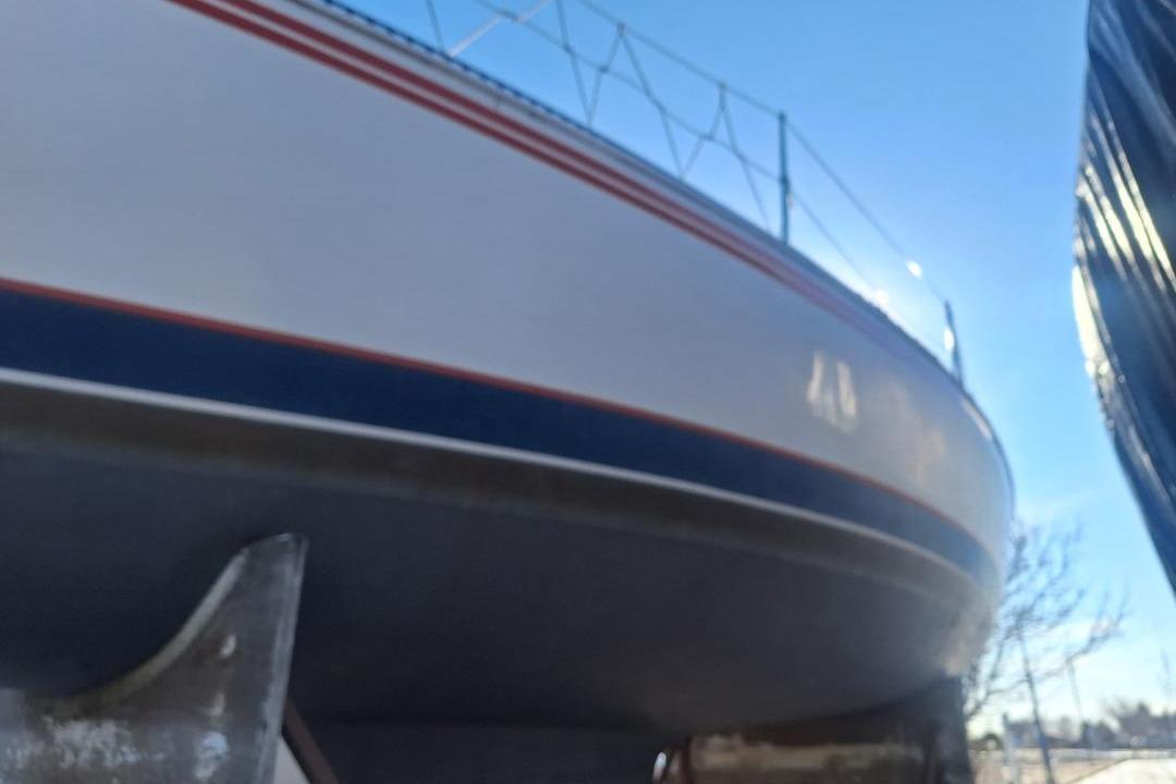 1983 Express 30 sailboat with red and blue stripes, viewed from below.