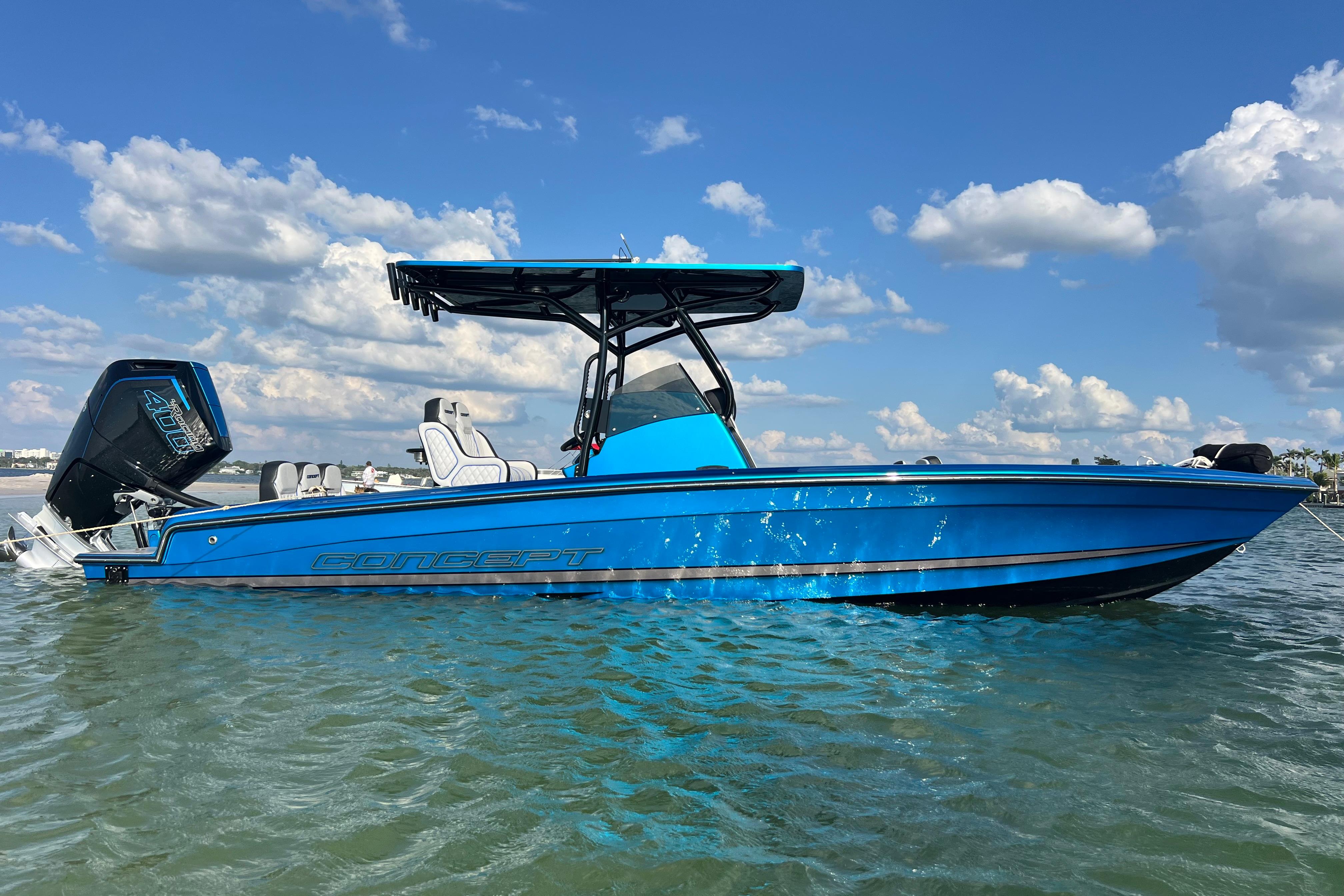 2025 Concept 27' Open Deck boat in vibrant blue on calm water under a clear sky.