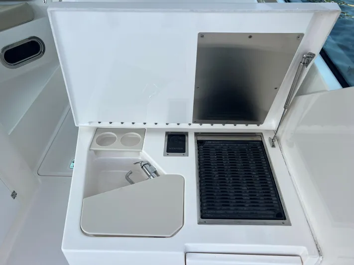 Pursuit 32dc Yacht Photos Pics 2015 Pursuit 325DC boat kitchenette with sink, grill, and storage compartments.