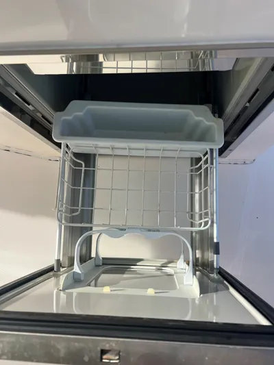 Pursuit 32dc Yacht Photos Pics Open storage compartment in a 2015 Pursuit 325DC boat, featuring a wire rack and tray.