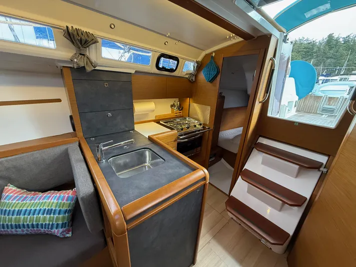 Seaglass Yacht Photos Pics Interior of 2019 Jeanneau Sun Odyssey 349 sailboat, featuring kitchen and seating area.