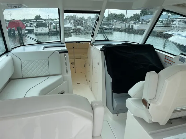  Yacht Photos Pics 2024 Pursuit DC 326 Dual Console interior with white seating, docked at marina.