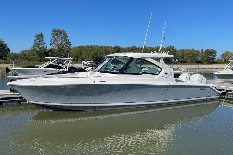  Yacht Photos Pics 2024 Pursuit DC 326 Dual Console boat docked on calm water under clear blue sky.