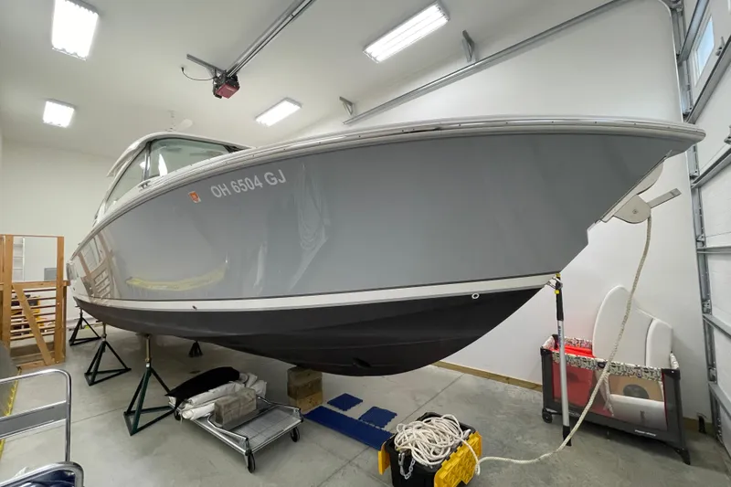  Yacht Photos Pics 2024 Pursuit DC 326 Dual Console boat in garage, elevated on stands.