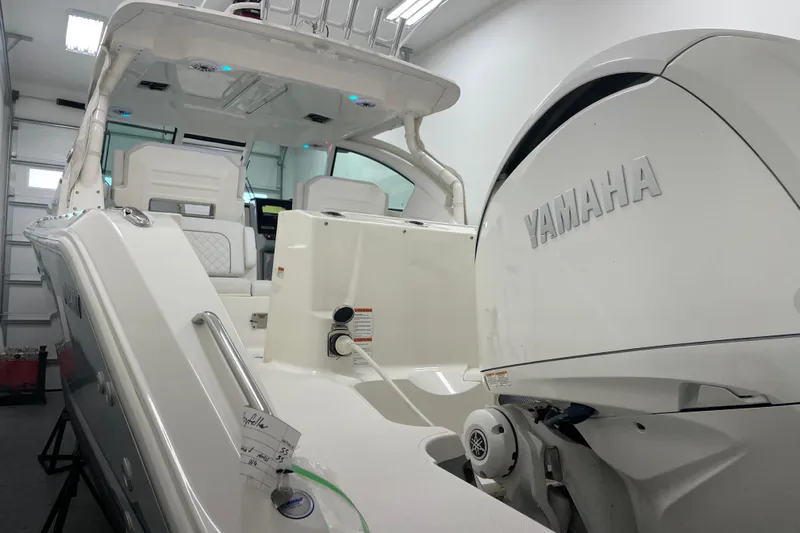  Yacht Photos Pics 2024 Pursuit DC 326 Dual Console boat with Yamaha engine in a garage setting.