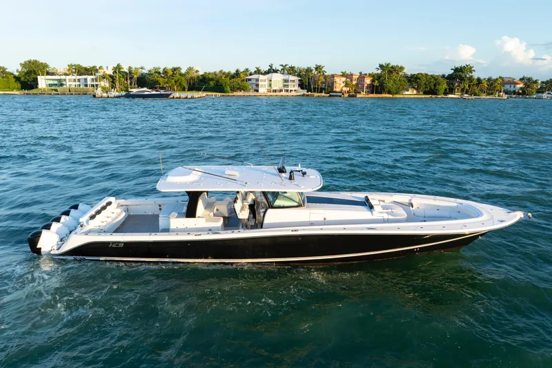  Yacht Photos Pics 2021 HCB 65 Estrella luxury boat cruising on a sunny day near waterfront homes.