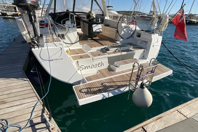 Smooth Yacht Photos Pics Beneteau Oceanis 45 sailboat docked, rear view, 2012 model, with wooden deck and red flag.