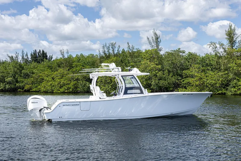  Yacht Photos Pics 2024 Sportsman Open 322 Center Console boat on calm water, surrounded by lush greenery.