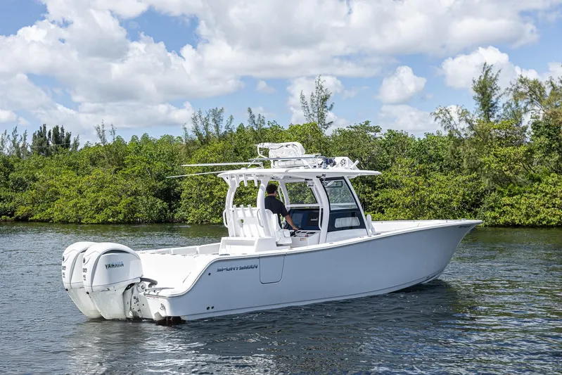  Yacht Photos Pics 2024 Sportsman Open 322 Center Console boat on water, surrounded by lush greenery.