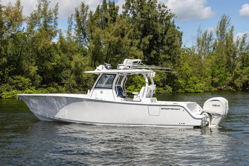  Yacht Photos Pics 2024 Sportsman Open 322 Center Console boat on calm water, surrounded by lush greenery.