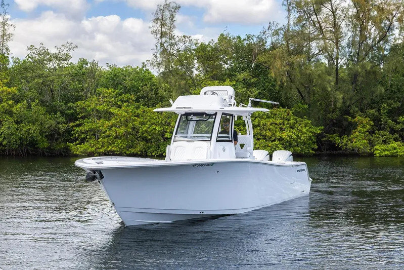  Yacht Photos Pics 2024 Sportsman Open 322 Center Console boat on calm water, surrounded by lush greenery.