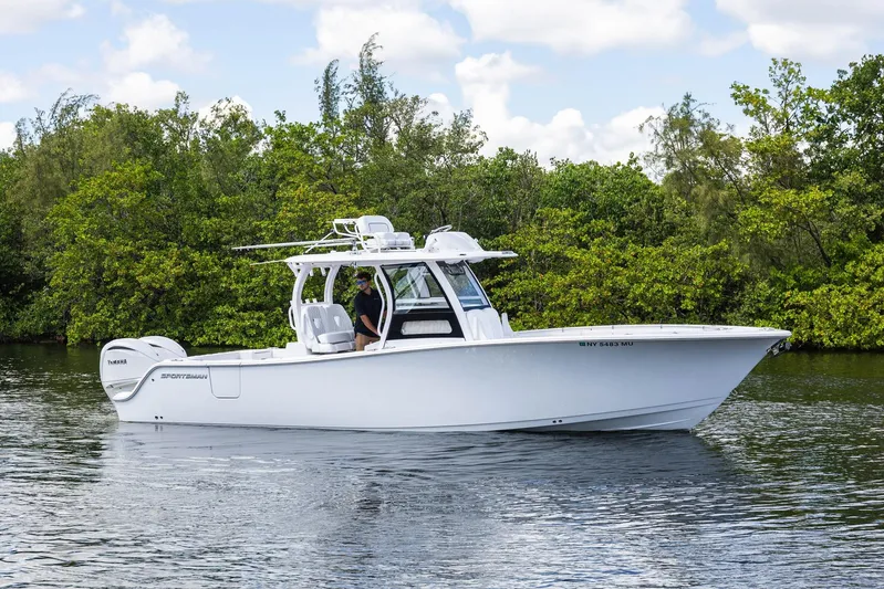  Yacht Photos Pics 2024 Sportsman Open 322 Center Console boat on calm water, surrounded by lush greenery.
