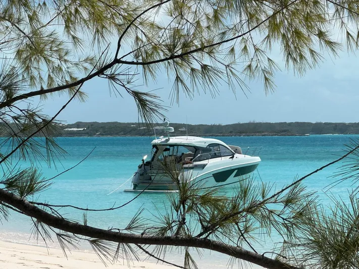  Yacht Photos Pics 2021 Beneteau Gran Turismo 41 yacht anchored in turquoise waters, framed by tropical foliage.