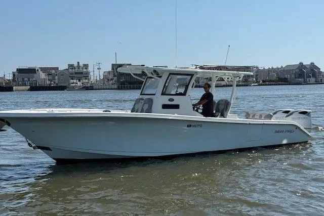  Yacht Photos Pics 2022 Sea Pro 320 DLX Offshore boat cruising on calm waters near a coastal town.
