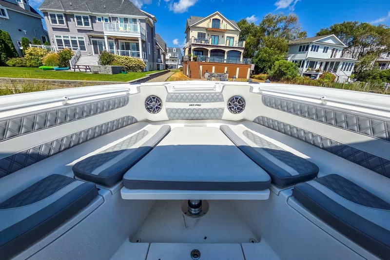  Yacht Photos Pics 2022 Sea Pro 320 DLX Offshore boat interior with cushioned seating, docked near waterfront homes.