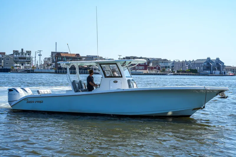  Yacht Photos Pics 2022 Sea Pro 320 DLX Offshore boat cruising on calm waters near coastal homes.