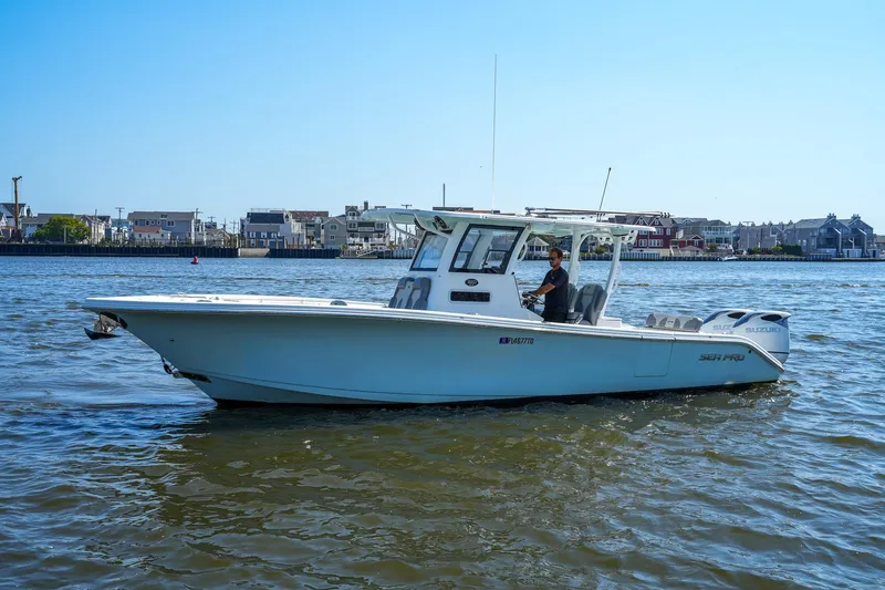  Yacht Photos Pics 2022 Sea Pro 320 DLX Offshore boat cruising on a sunny day near coastal homes.