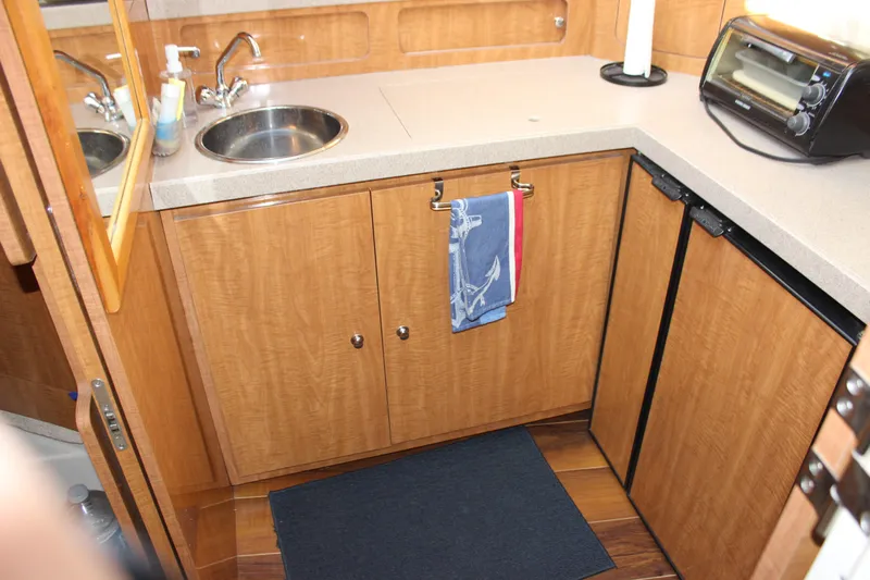  Yacht Photos Pics 2002 Regal Commodore 3880 yacht kitchen with sink, countertop, and wooden cabinets.
