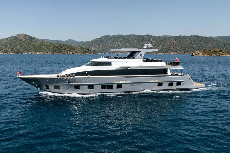  Yacht Photos Pics Luxury 1988 Heesen 32 yacht cruising in scenic blue waters, surrounded by lush green hills.
