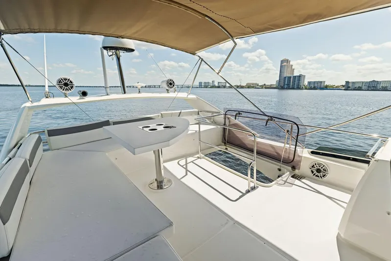  Yacht Photos Pics 2018 Prestige 460 yacht deck with seating and table, overlooking waterfront cityscape.