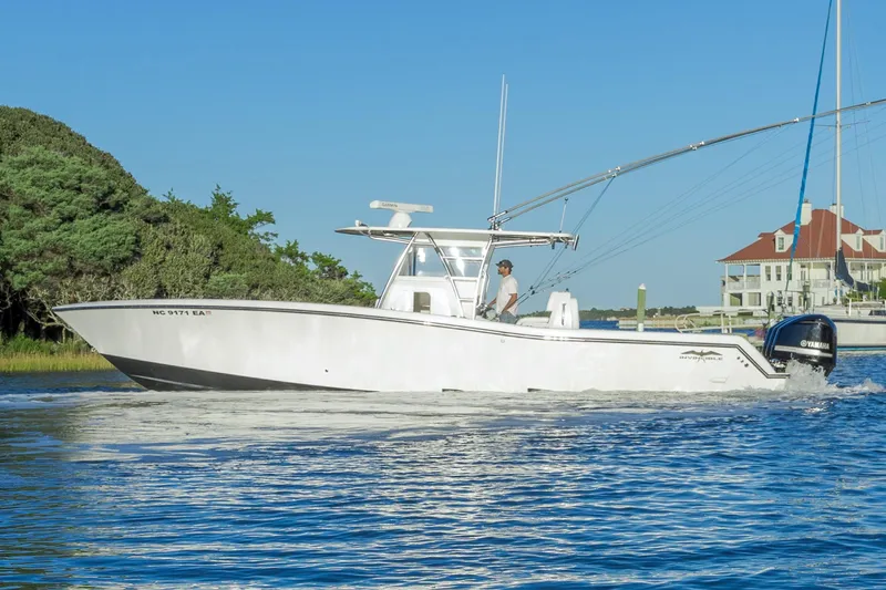  Yacht Photos Pics 2015 Invincible 39 Open Fisherman boat cruising on a sunny day near a coastal house.