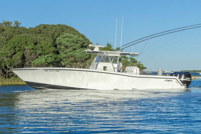  Yacht Photos Pics 2015 Invincible 39 Open Fisherman boat on calm water near lush greenery.