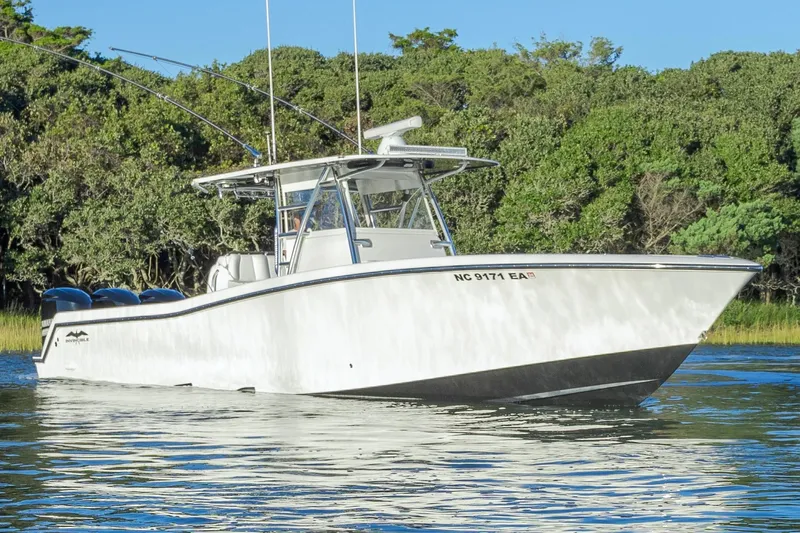  Yacht Photos Pics 2015 Invincible 39 Open Fisherman boat on calm water, surrounded by lush greenery.