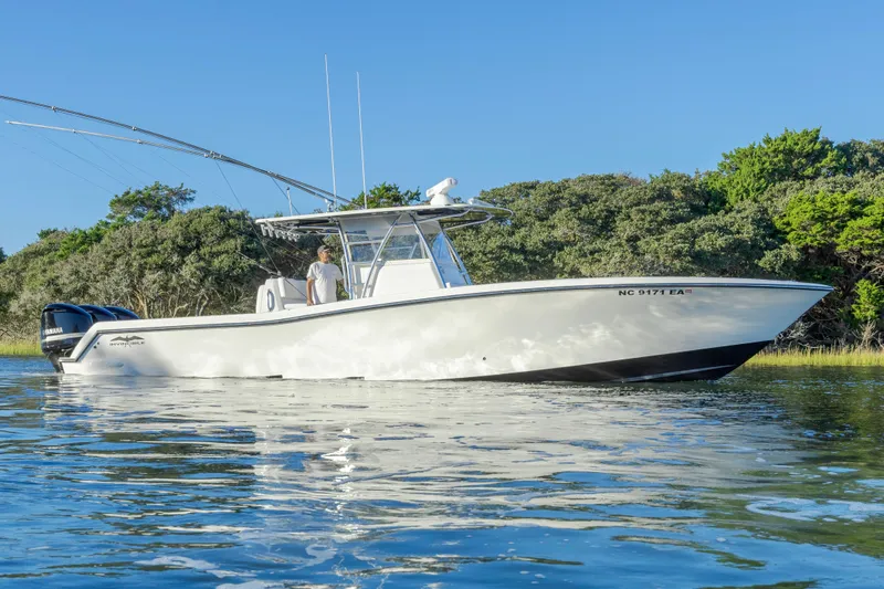  Yacht Photos Pics 2015 Invincible 39 Open Fisherman boat on calm water, surrounded by lush greenery.