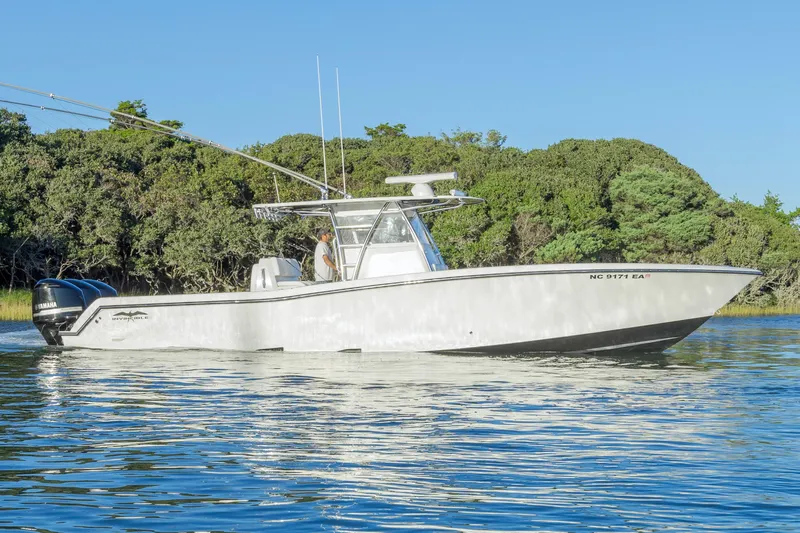  Yacht Photos Pics 2015 Invincible 39 Open Fisherman boat on calm water, surrounded by lush greenery.