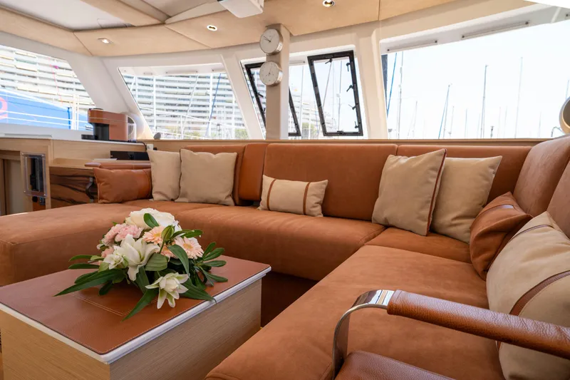  Yacht Photos Pics Luxurious interior of 2023 Fountaine Pajot Isla 40 catamaran with plush seating and floral centerpiece.